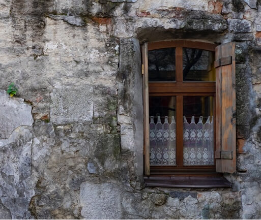 Gracefully aged hertiage building wall with a wood framed window.